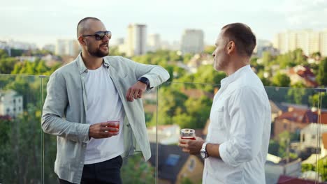 Two-happy-businessmen-are-holding-cocktails-and-posing.-Meeting-of-friends---businessmen.-Celebration-of-and-important-event