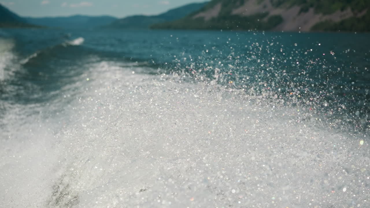 Sparkling splashes on surface of lake after boat moving. Picturesque landscape with foamy water surface. Movement of water in natural reservoir slow motion