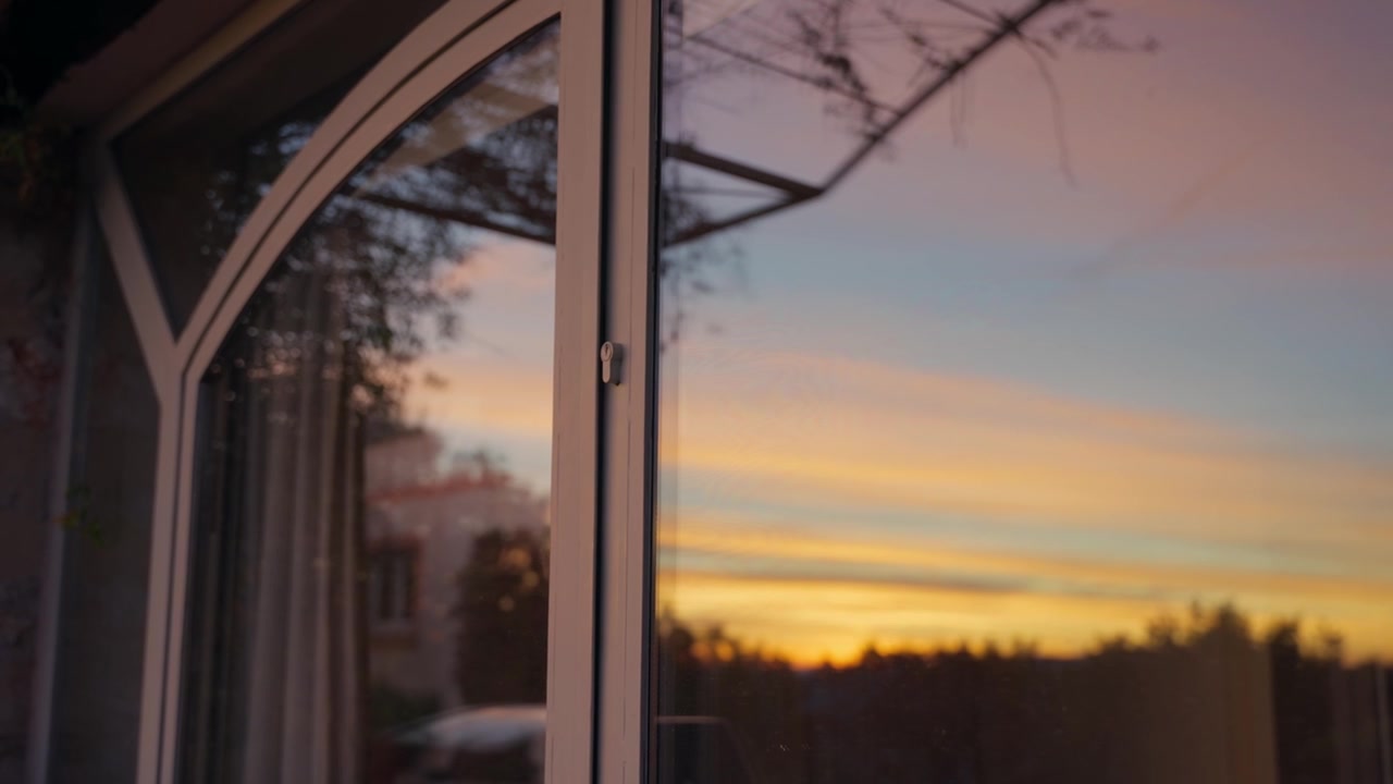 Dramatic golden sunset reflecting in a glass door with a soft, blurred background, creating a serene and contemplative atmosphere of tranquility and natural beauty at dusk