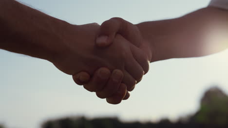 Caucasian people shaking hands outdoors. Two business partners on summer nature.