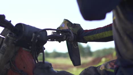 motocross dirt bike rider hand on throttle handle grip and goggles, cinematic slow motion close-up with motorcycle details