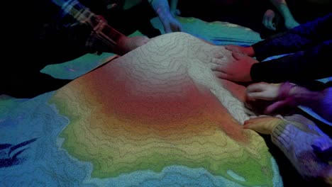 people playing with an augmented reality sandbox