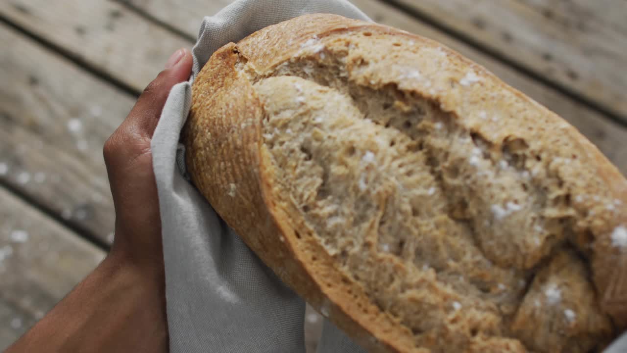 Baker's hands lifting loaf over wood table causing marketing icons fluctuating showing engagement