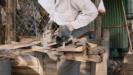 worker sharpening a broad blade with a grinding wheel