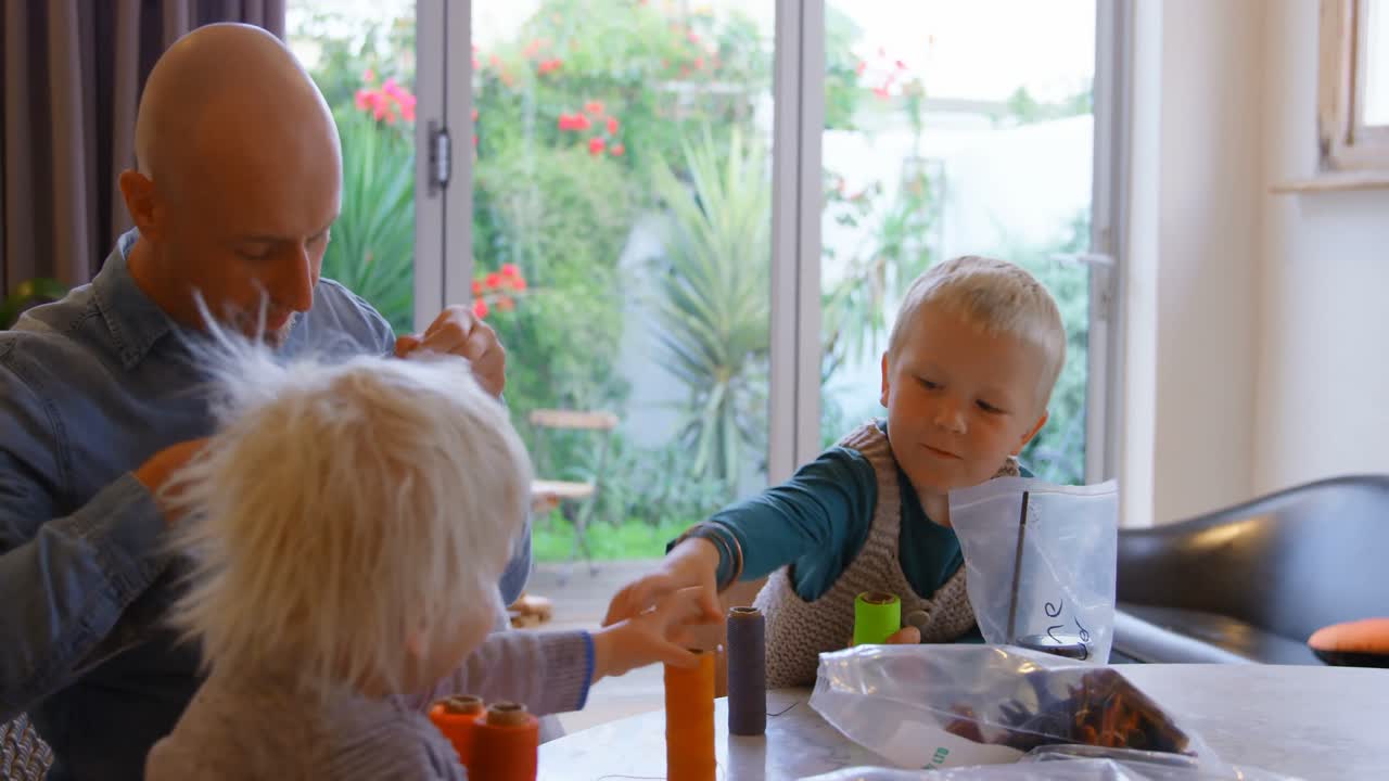 Padre che mostra ai figli i rocchetti di filo nel soggiorno di casa 4k
