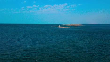 An-aerial-view-of-el-biben-island-with-a-pool-and-hosting-houses-sits-in-the-middle-of-the-ocean-with-palm-trees-on-it,-surrounded-by-water-creating-a-beautiful-atmosphere