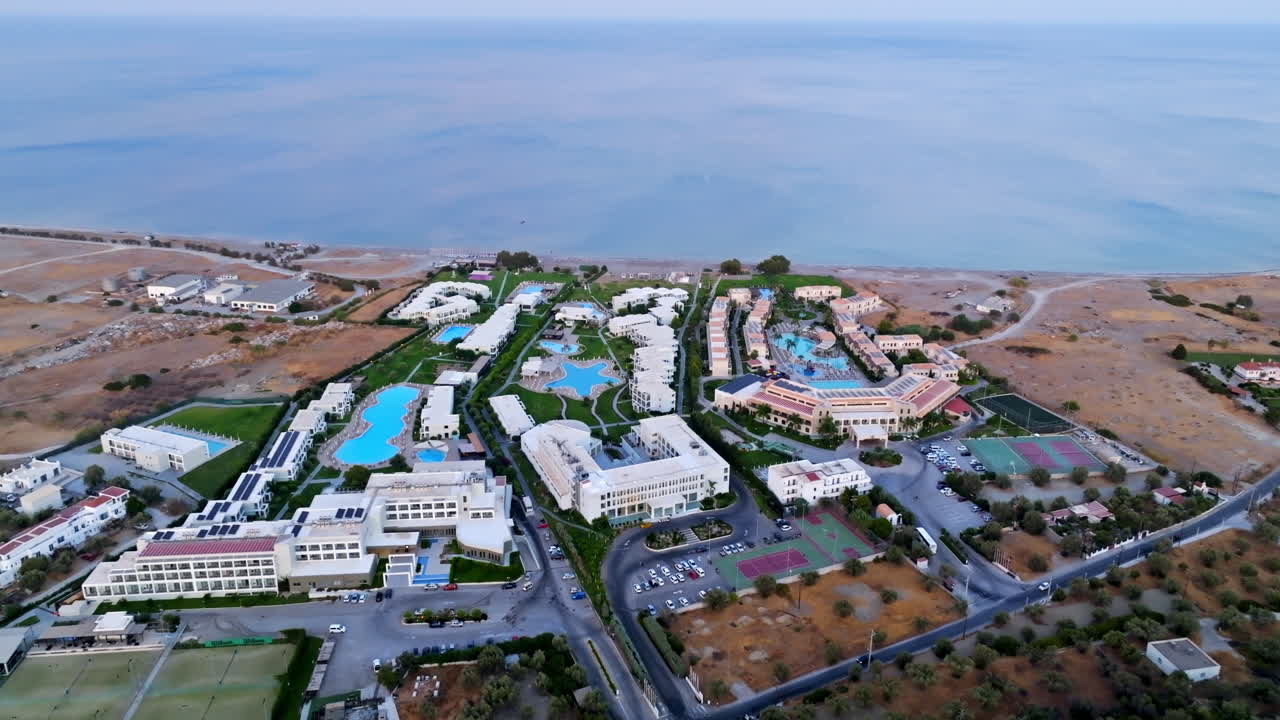 그리스 해안의 큰 호텔 단지에서 멀리 기울어지는 공중 사진, 황혼