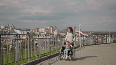 woman walks on viewpoint with daughter sitting in wheelchair