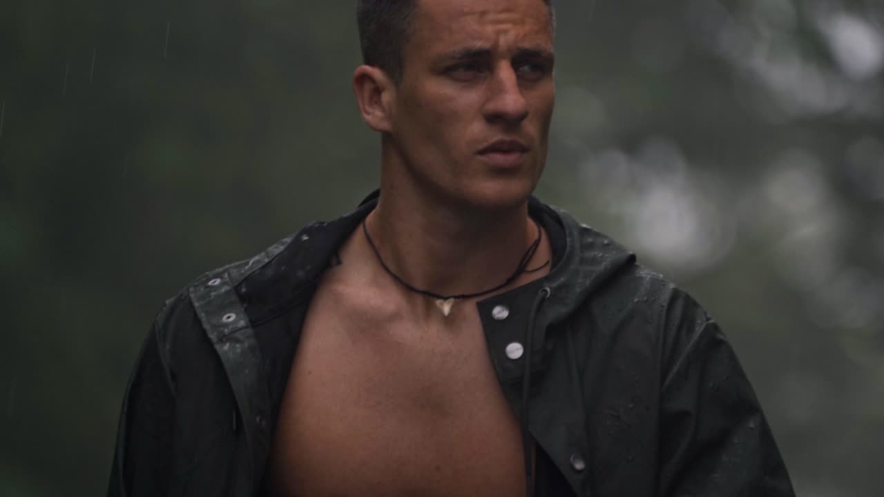 A man walks shirtless in the rain through a misty, green landscape in San Carlos, Costa Rica