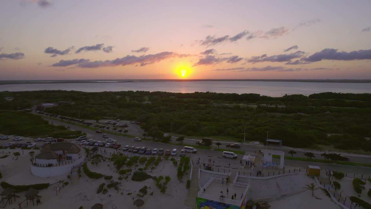 Large Bright Orange Sunset Sun On Ocean Horizon With Luxury Tourist Resorts On Shore Of Playa Delfines, Cancun Mexico, 4K Drone