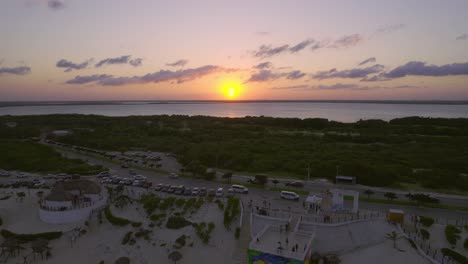 gran puesta de sol naranja brillante en el horizonte del océano con resorts turísticos de lujo en la orilla de playa delfines, cancún méxico, dron 4k