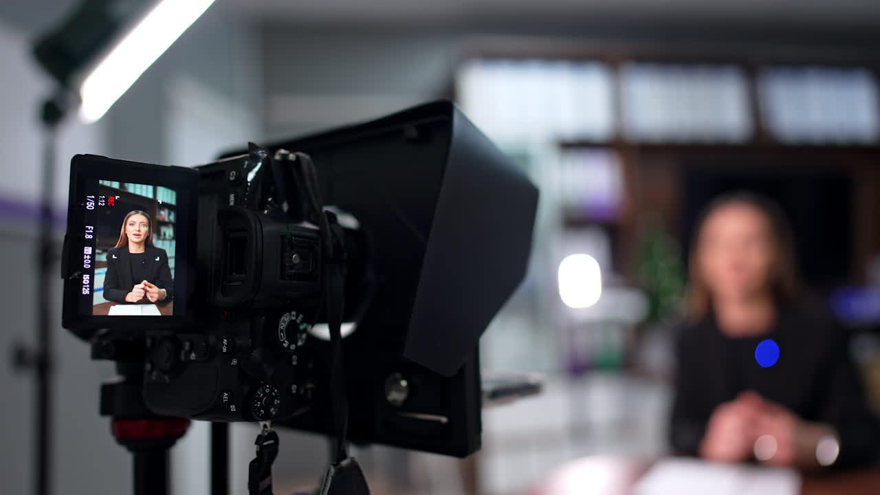 Working camera with display and a brunette lady on it. Close up. Blog content creation in studio. Blurred backdrop.