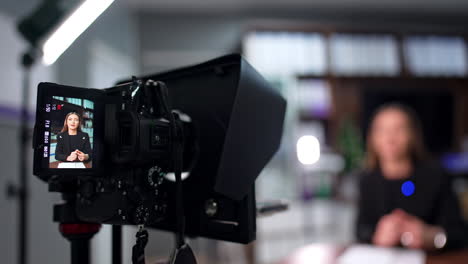 working camera with display and a brunette lady on it. close up. blog content creation in studio. blurred backdrop.