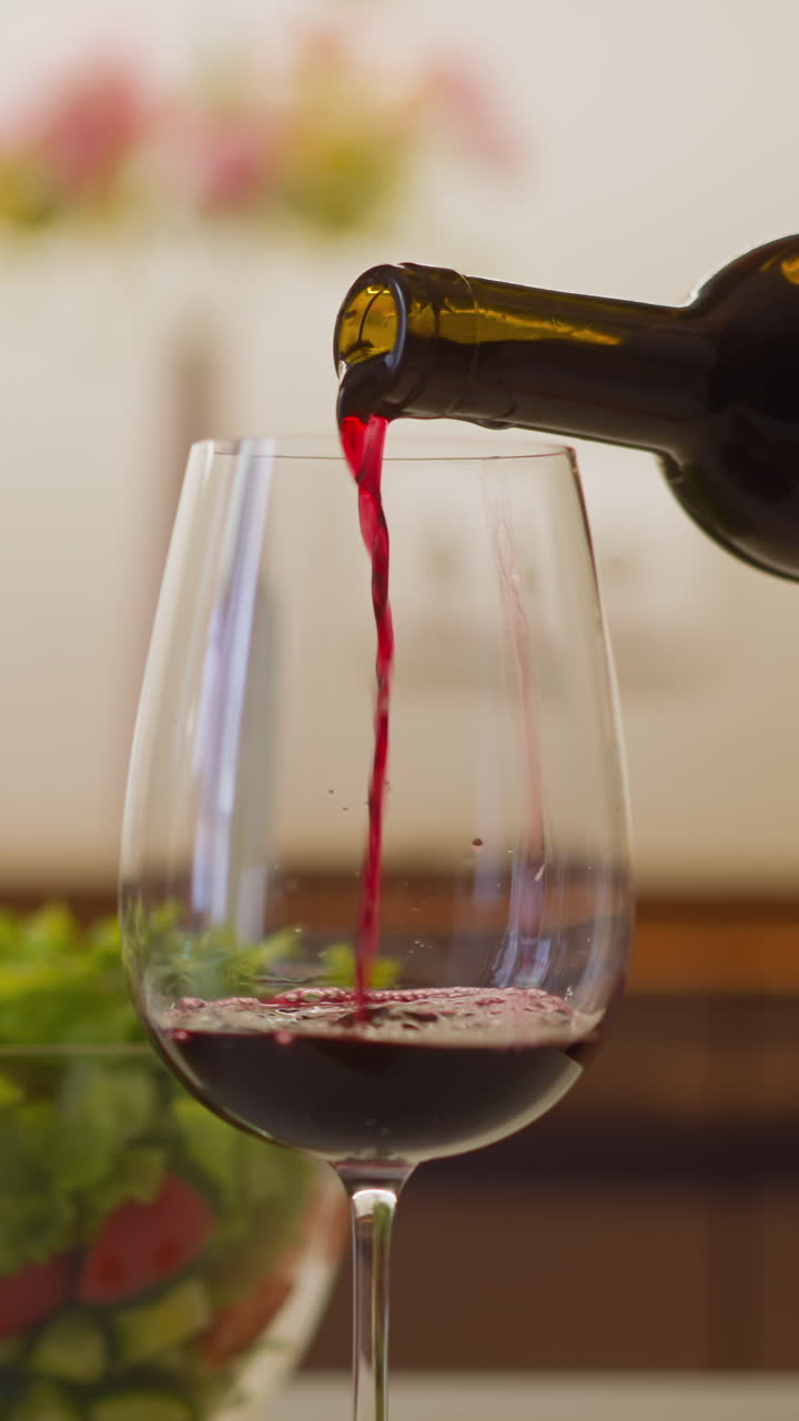 Person pours delicious red wine into elegant wineglass from bottle preparing festive romantic dinner at home extreme close view slow motion