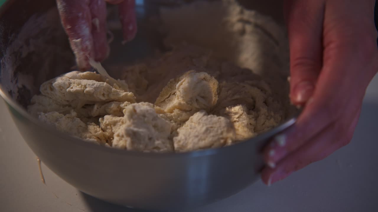 Close-up of Hands Mixing Dough in a Metal Bowl