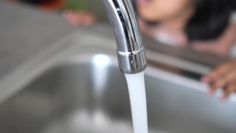 child playing with water from a kitchen tap