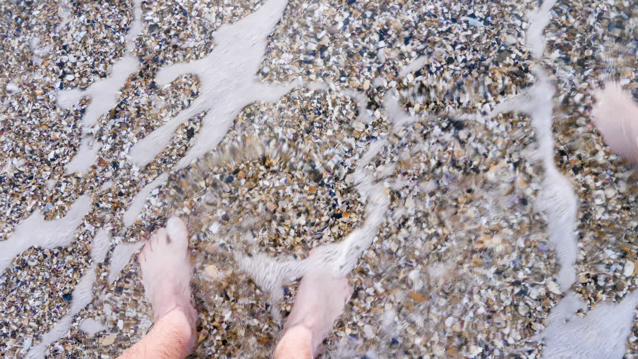 POV feet in water on the beach