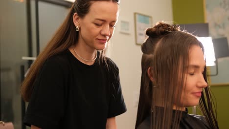 Hair Stylist Trimming Client Hair with Scissors During a Beauty Treatment in a Salon. A hair stylist trims hair with scissors during a beauty treatment in a professional salon