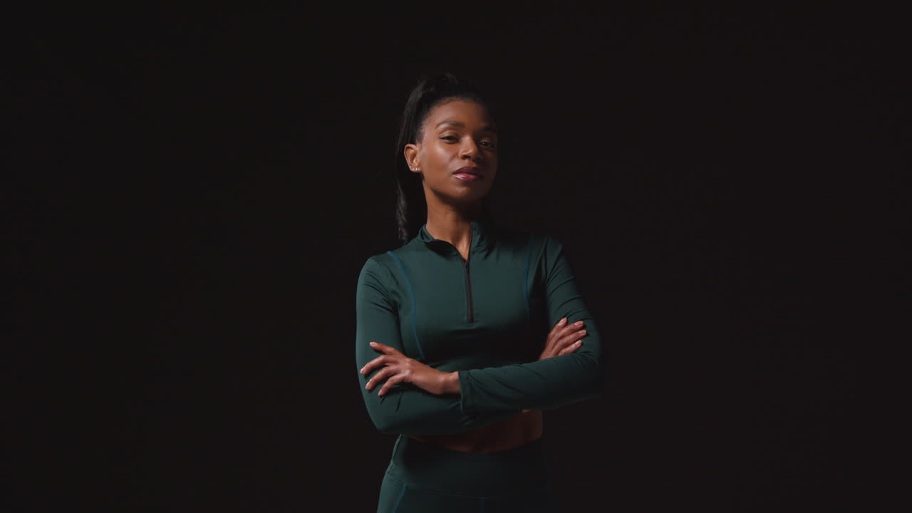 retrato de una atleta femenina decidida que lleva un traje de entrenamiento y se prepara psicológicamente para un evento deportivo contra un fondo de estudio negro 2
