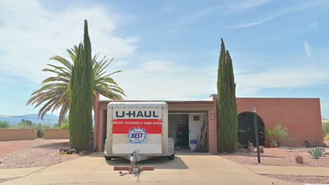 remolque u-haul estacionado frente a una casa con garaje abierto