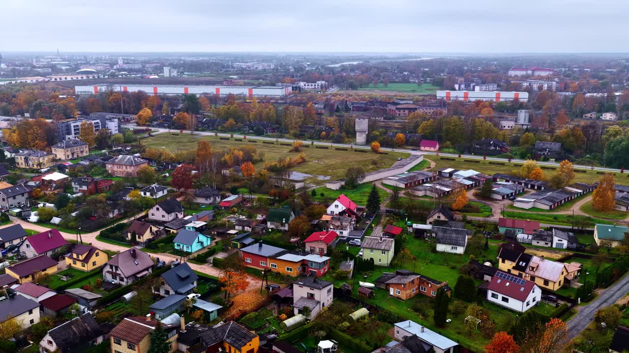 A Colorful Town Lies Under a Cloudy Autumn Sky - Aerial Drone Shot