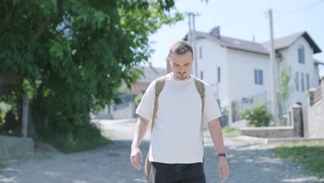 young man walking with guitar on street near forest