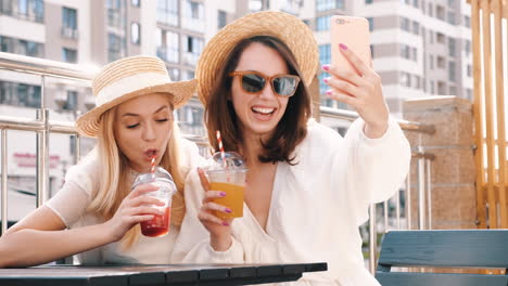 two happy friends enjoying drinks and taking a selfie outdoors