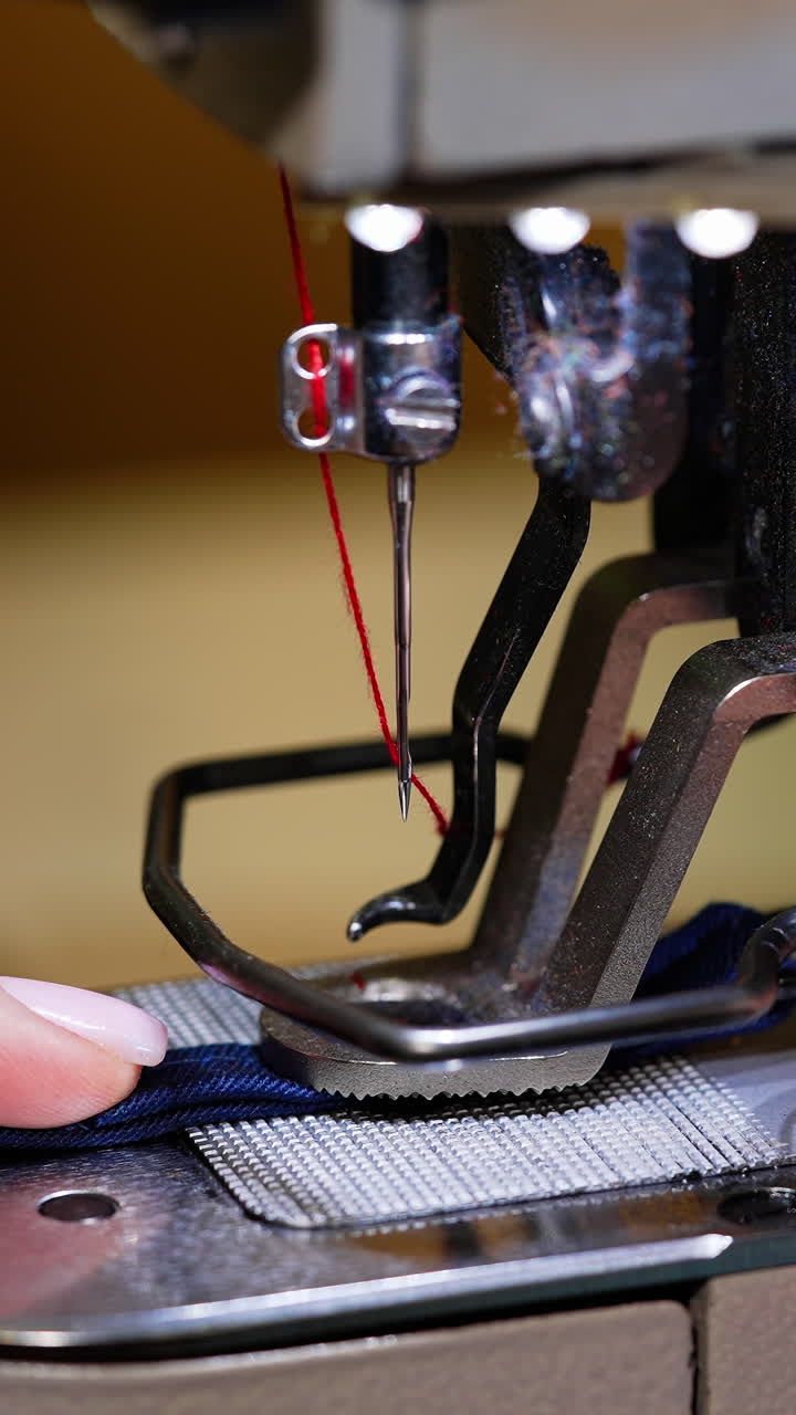 Woman using sewing machine in factory. Female hands working on tailoring industrial fabric. Vertical video
