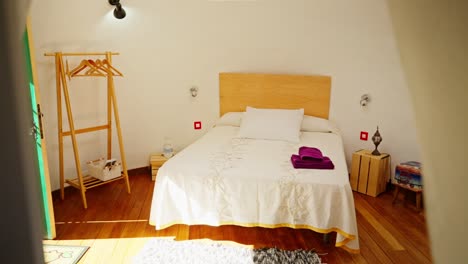 small furnitured bedroom with wooden floor, decoration, view shot through object