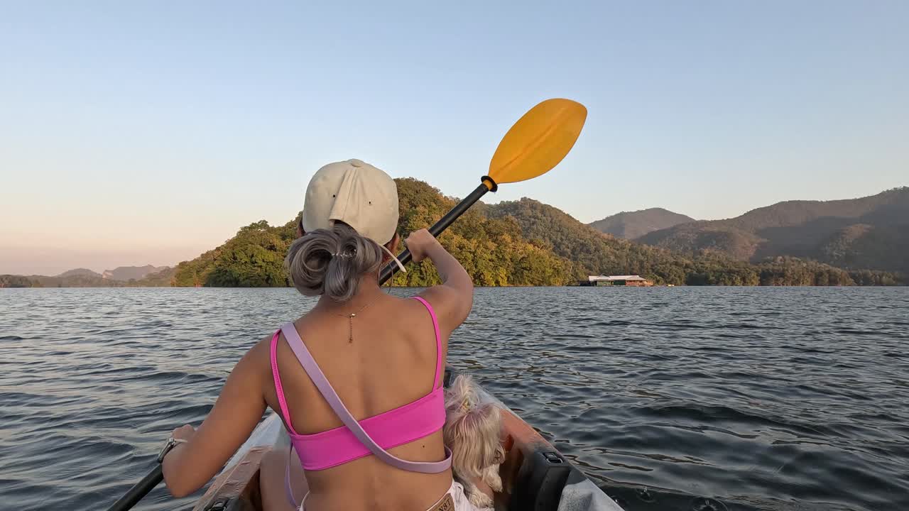 mujer y perro en kayak en aguas serenas al anochecer