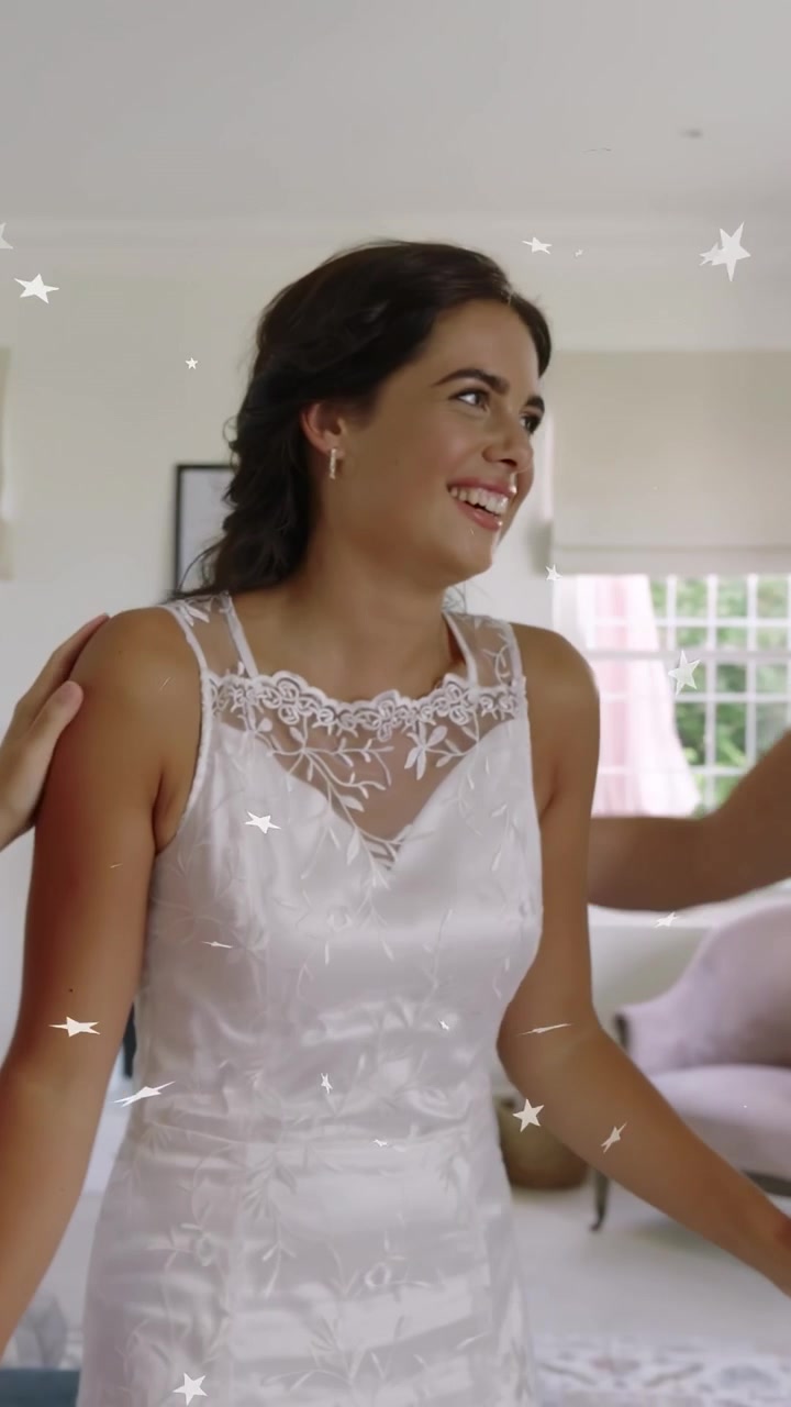 Video vertical: Novia estirándose, ayudante sosteniendo un vestido de encaje, novia dando vueltas para una sesión de fotos nupcial.