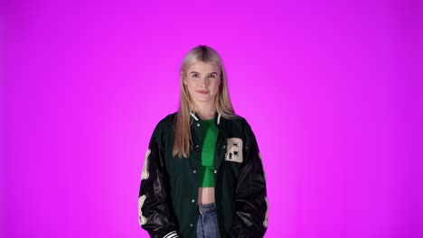 young blonde woman waving hand, greeting gesture against purple color background, studio shot