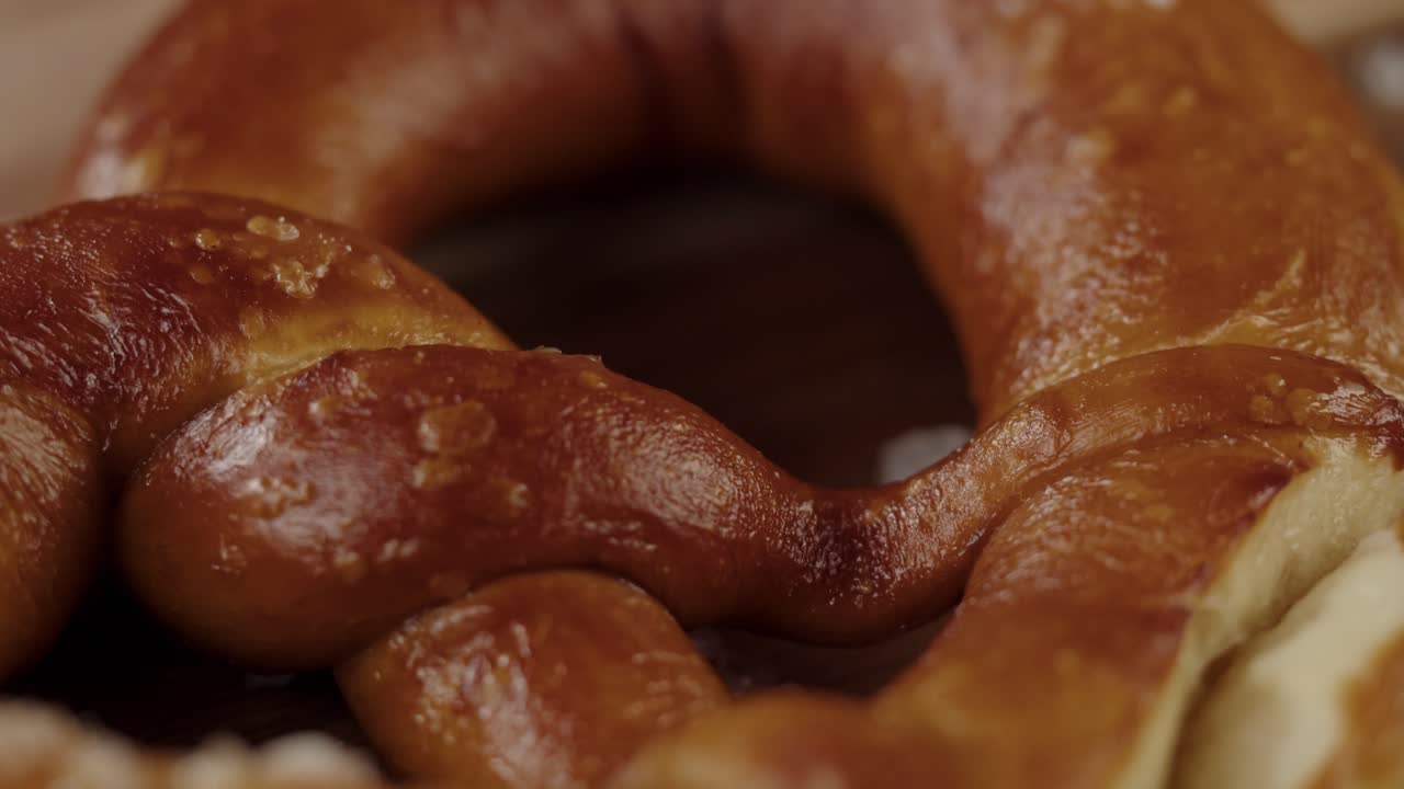 Lähikuva kullanruskeasta, pehmeästä pretzelistä karkealla suolalla.