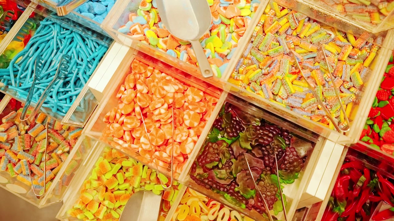 Deslizamiento de arriba hacia abajo, coloridas cajas de dulces mostrando variedad de texturas y tonos vivos