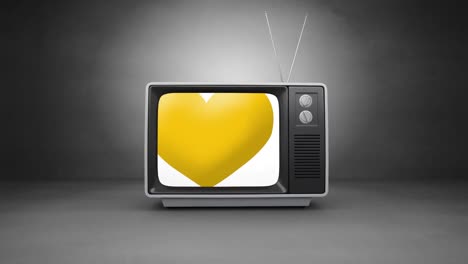 digital animation of yellow heart icon on television screen against grey background