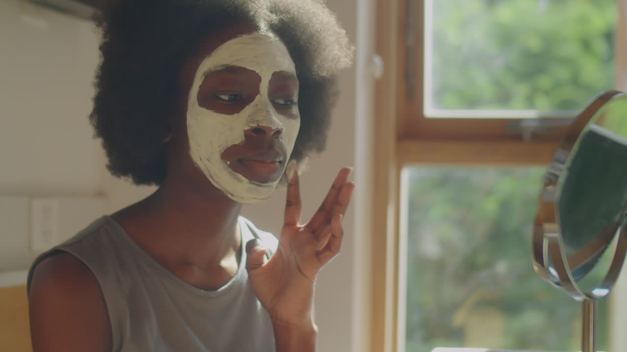 African American Woman Applying Clay Mask to Facial Skin