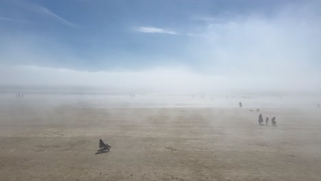 People-enjoy-walking-on-foggy-sand-beach-in-sunny-Tramore,-Ireland
