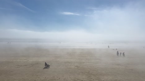 people enjoy walking on foggy sand beach in sunny tramore, ireland