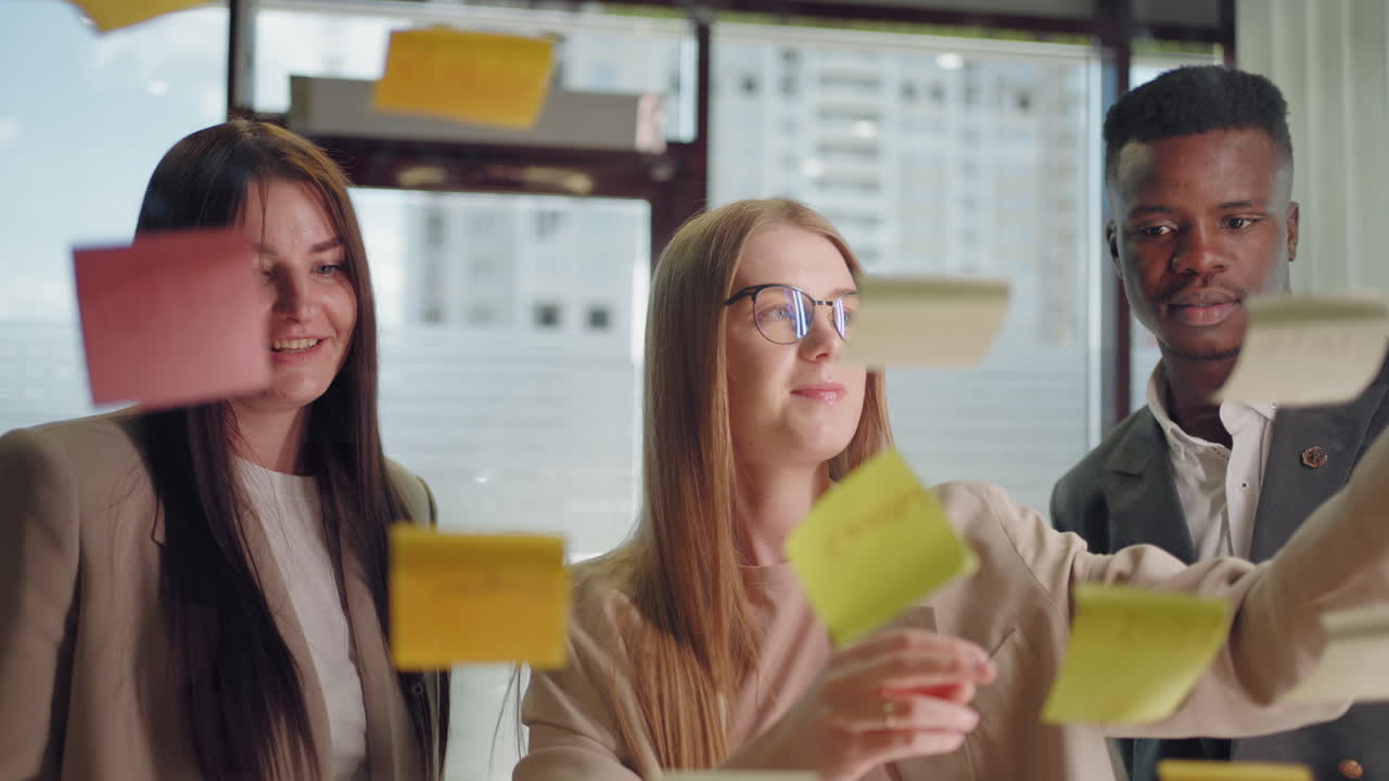 creative marketing specialists are brainstorming in office sticking post-it notes on glass wall