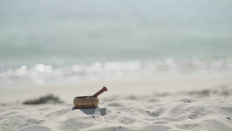 cuenco de canto tibetano de bronce para la meditación en la playa de mar de arena
