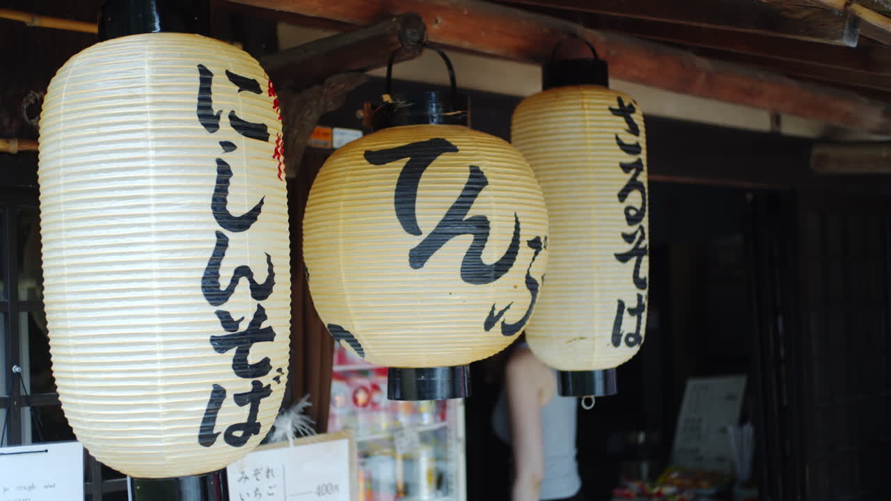 일본 교토의 부드러운 조명에 전통적인 아시아 랜터가 걸려 있는 레스토랑에서 고객이 걸어 나옵니다.