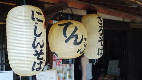 Customer-walking-out-of-a-restaurant-with-traditional-asian-lanters-hanging-in-Kyoto,-Japan-soft-lighting