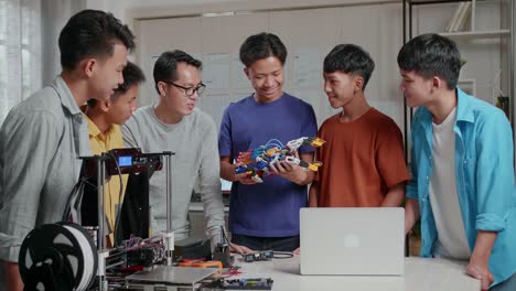 asian man and the boys with a laptop and 3d printing checking a cyborg hand at school