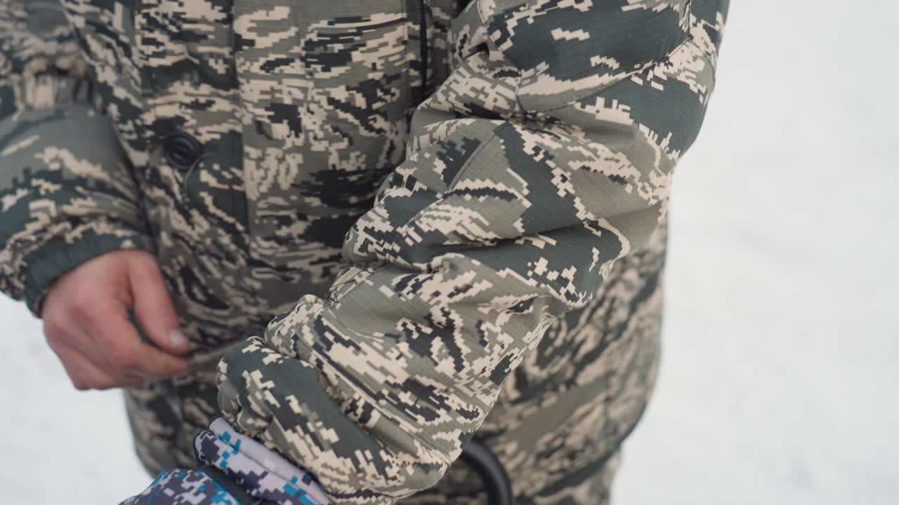 Lumiseikkailuun valmistautuva ajaja. Varmistaa varusteiden kunnon ankariin talviolosuhteisiin. Tarkastaa huolellisesti käsineet ja rannehihnat taatakseen turvallisuuden äärimmäisen talviseikkailun aikana.