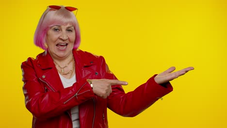 mature grandmother showing thumbs up and pointing empty place, advertising area for commercial text