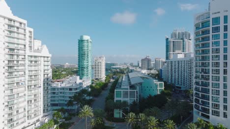 modern urban borough with tall apartment buildings in tropical on sunny day. forwards fly above road lined with palm trees. miami, usa