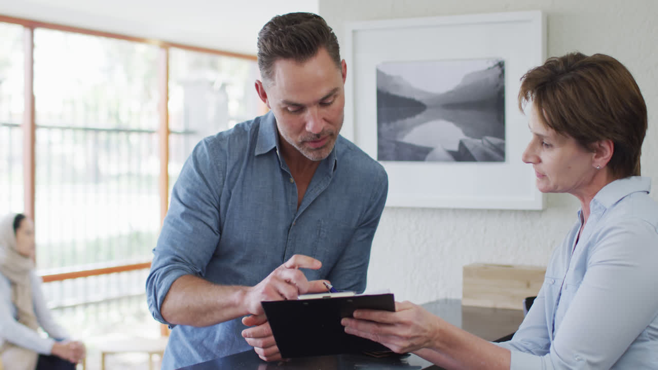 hombre caucásico sonriente hablando y firmando documentos en la recepción de una clínica dental moderna