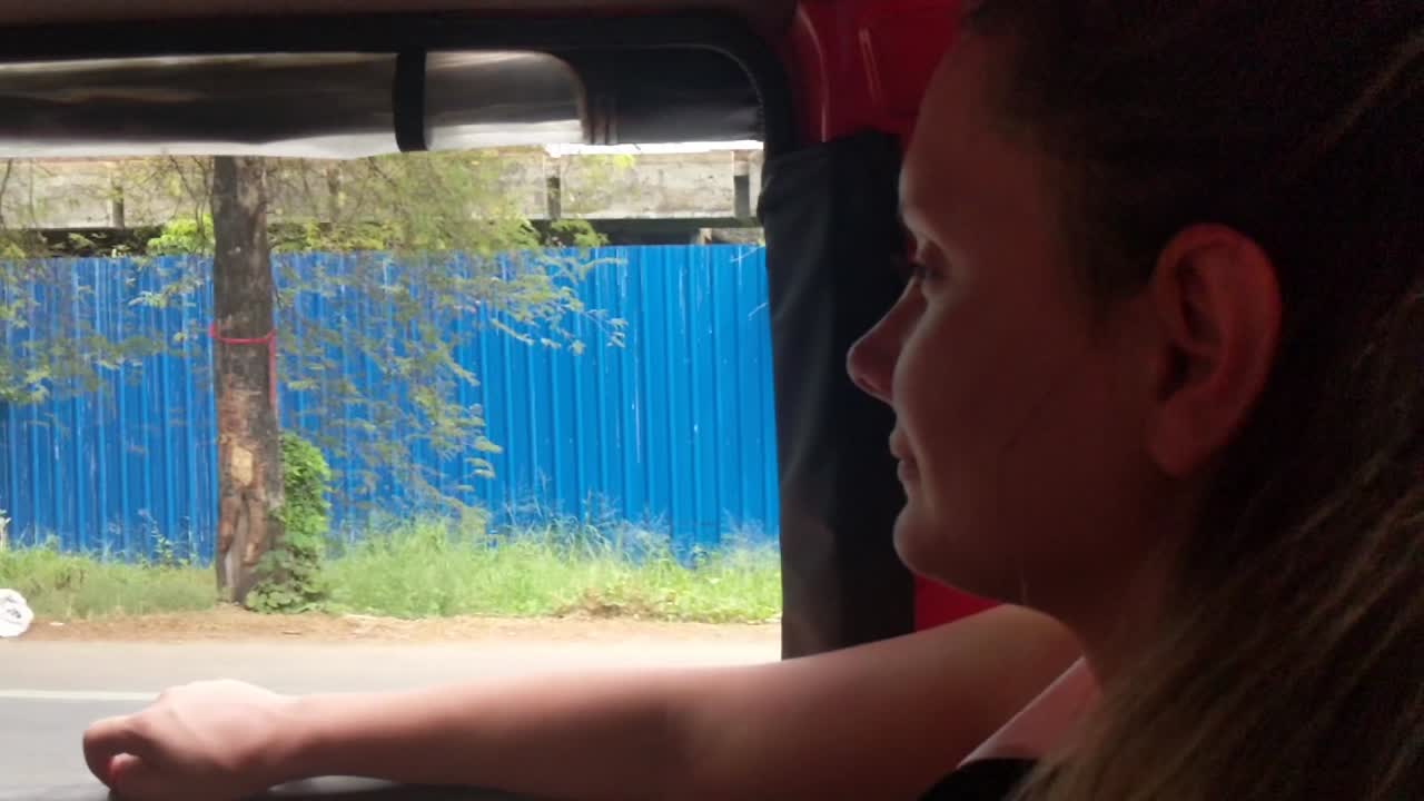 Happy Tourist in the back of Auto Rickshaw Looks out at the Traffic Zooming Past at Alleppey, Kerala, India