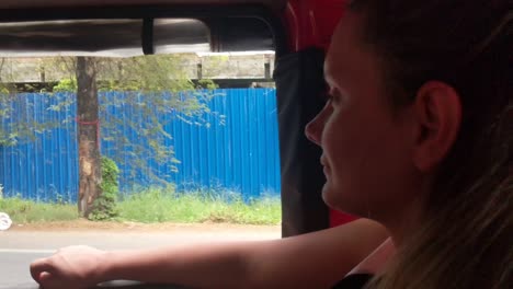 happy tourist in the back of auto rickshaw looks out at the traffic zooming past at alleppey, kerala, india