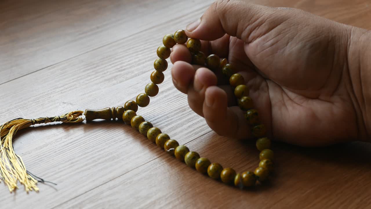 무슬림 남자 가 손 에  rosary 구슬 을 들고 기도 하고 있다